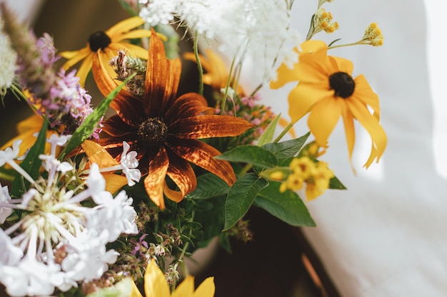 Wildflowers boeket op achtergrond van houten stoel met wit kussen in zonnige rustieke kamer Zomer op het platteland Home eenvoudige eco decor mooie gele bloemen