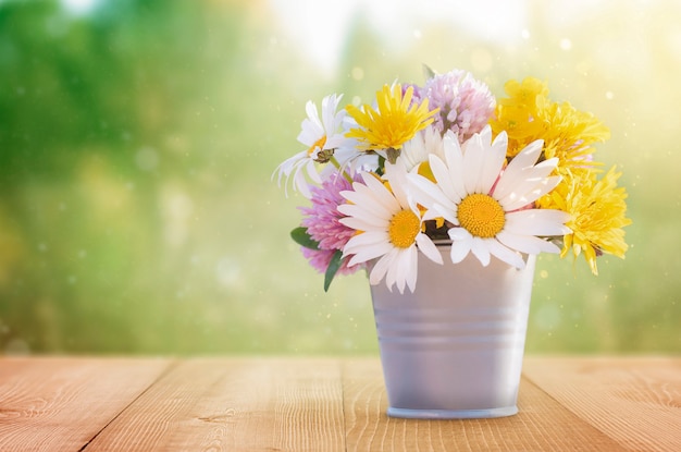 Wildflowers in a metal bucket on a wooden table