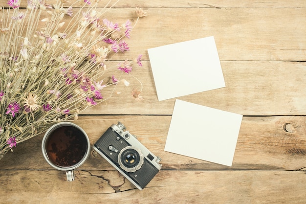 Wildflowers, metal cup of tea, a compass and other attributes for a hike on a wooden surface. Concept of hiking in the mountains or the forest, tourism, tent rest, camp. Flat lay, top view.