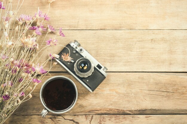 Wildflowers, metal cup of tea, a compass and other attributes for a hike on a wooden surface. Concept of hiking in the mountains or the forest, tourism, tent rest, camp. Flat lay, top view.