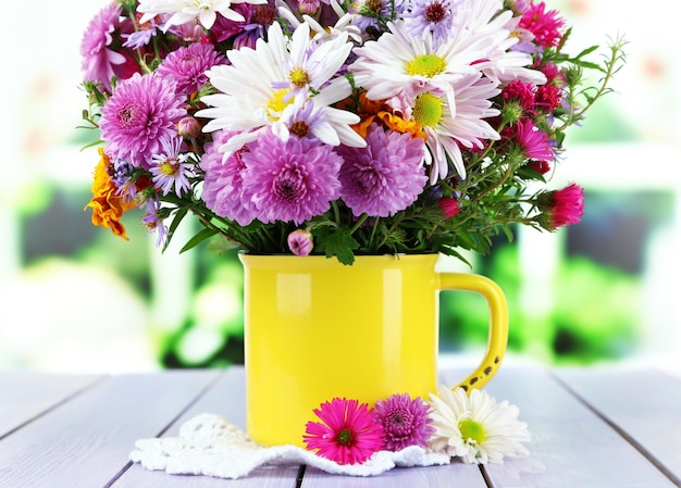 Wildflowers in mug on napkin on wooden table on window background