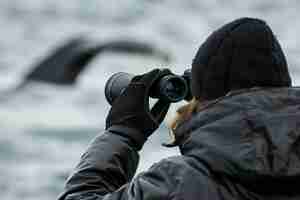 Photo wildlife spotter with binoculars tracking a whale
