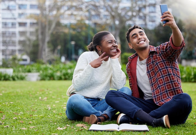 Will break for selfies. Shot of a young man and woman taking selfies on a study break at college.