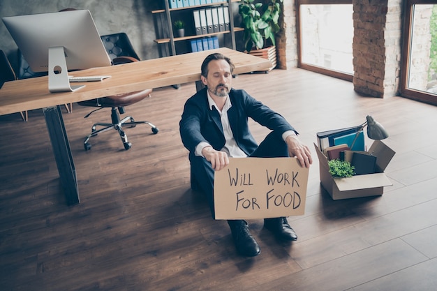 Foto funzionerà per il concetto di cibo. foto di disperato triste lavoratore infruttuoso maturo licenziato agente perdente perso il lavoro imballato scatola degli effetti personali crisi finanziaria sedersi piano cartone cartellone ufficio al chiuso