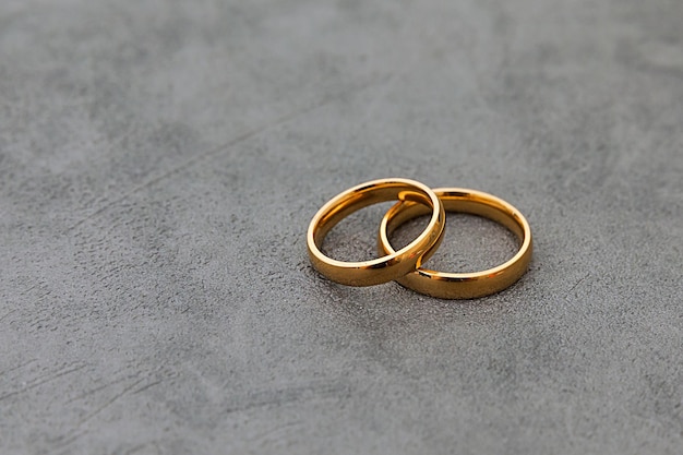 Will you marry me two golden wedding rings on concrete stone grey background engagement marriage pro