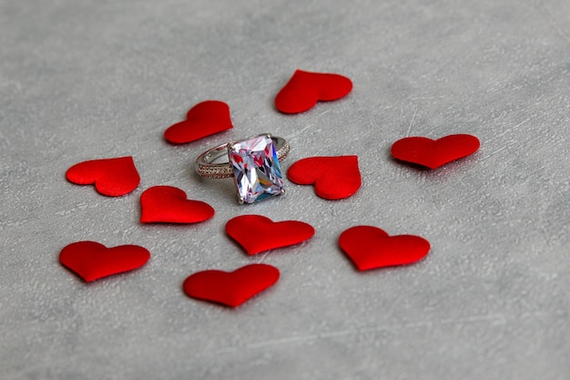 Ты выйдешь за меня замуж обручальное кольцо много красных сердец на бетонном сером фоне помолвки