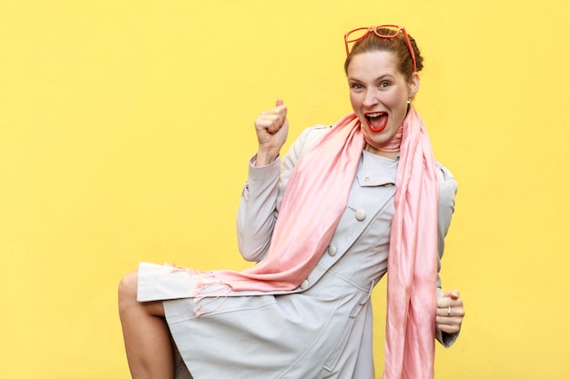 Win! Ginger woman rejoicing for his success. Isolated on yellow background. Studio shot