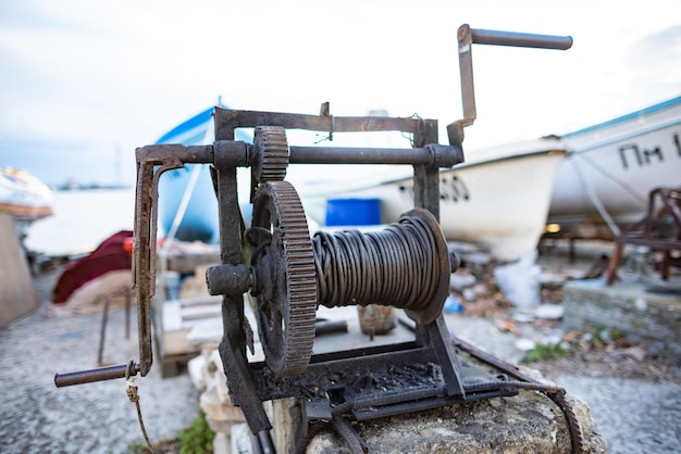 Winch with a rope on a pier with boats and boats against the sky