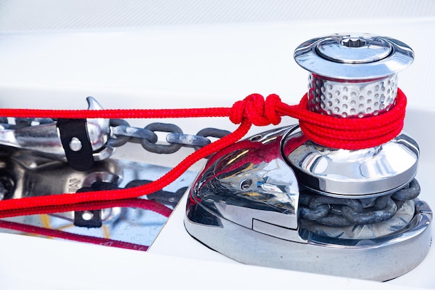 Winch on a yacht with an anchor chain and tied red rope