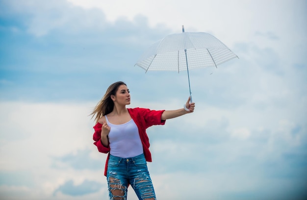 変化の風明るい傘を持ったきれいな女性虹色の傘雨天良い気分良い雰囲気良い空の背景を感じている女の子良い天気秋を迎える少女保護されている感じ