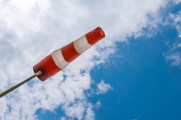 Wind direction indicator. A large red white striped windsock against blue sky