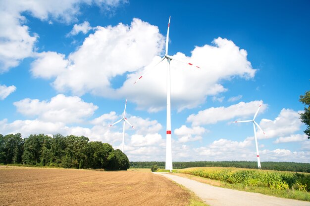 Wind farm in Lower Saxony, Germany. Turbines on field on cloudy blue sky. Alternative energy source. Global warming, climate change. Eco power, green technology concept.