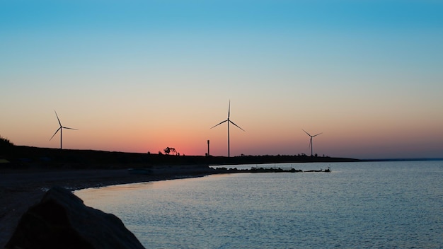 夜明けの海岸の風力発電所 風車発電 日の出の海の風景