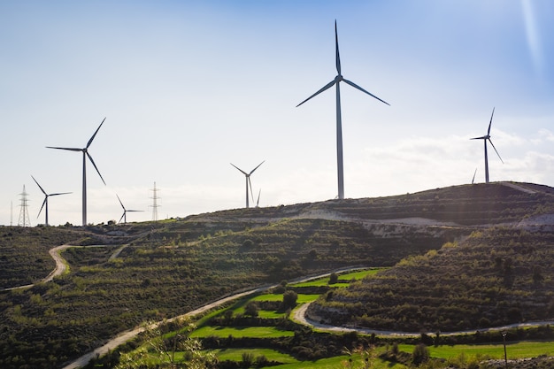 Wind mills during bright summer day. green meadow with Wind turbines generating electricity.