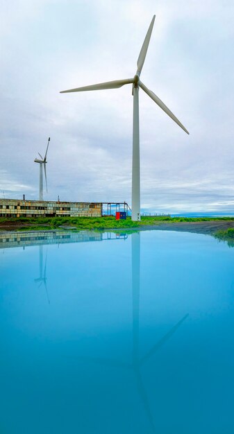 Wind power station on the shore with reflection in water.