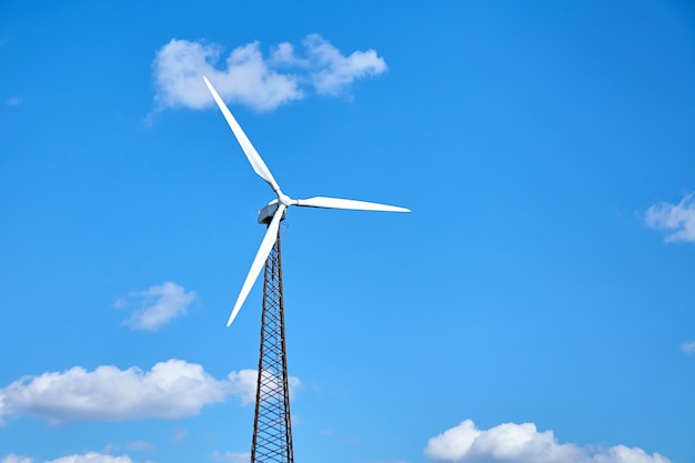 Wind power turbine against a blue sky with white clouds