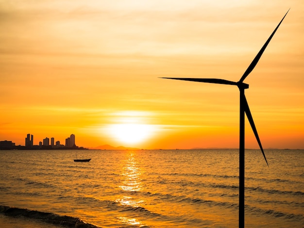 A wind turbine on the beach at sunset