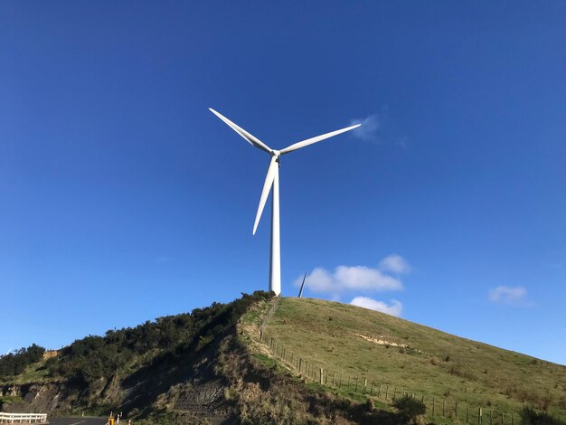 Una turbina eolica su una collina con una collina erbosa sullo sfondo nuova zelanda