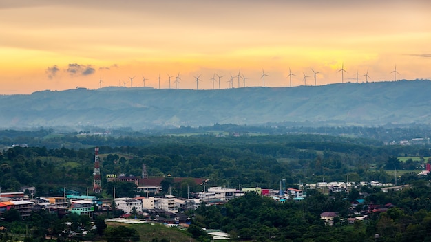 山頂に風力タービン。昼間の丘と明るい空。