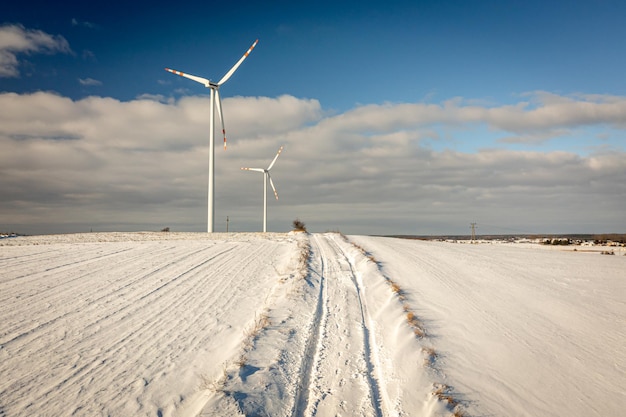 Ветряная турбина на снежном поле и проселочной дороге альтернативная энергия