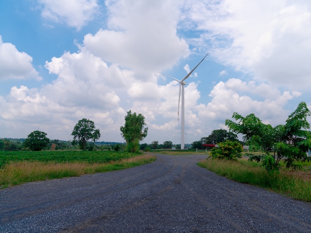 Turbina eolica con cielo blu nuvoloso in urbano con strada rocciosa, generatore di energia elettrica di energia verde, campo ecologico di fattoria del mulino a vento