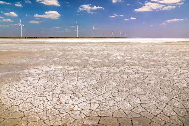 Wind turbines in desert with cracked earth at sunrise Green energy concept