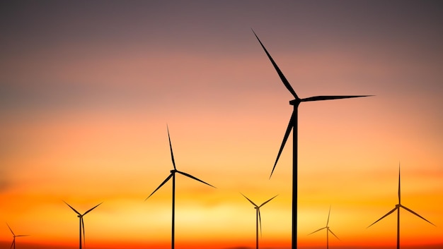 Wind turbines in front of a sunset with the sun setting behind them