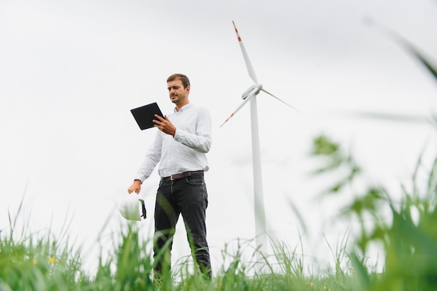 Wind turbines generating electricity. energy conservation concept and worker staff engineer hold tablet