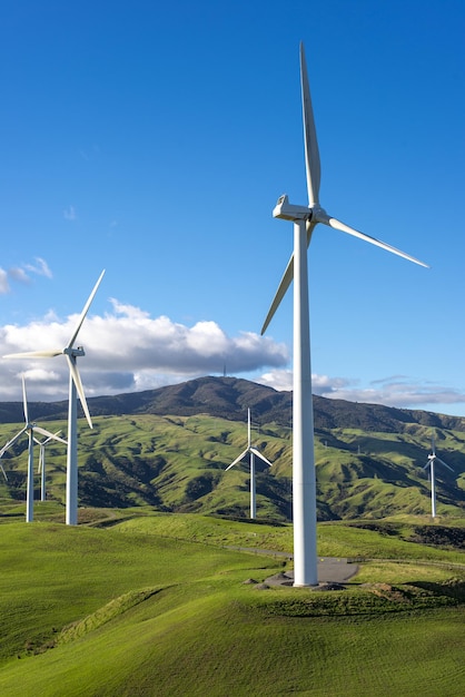 Wind turbines in a green meadow with mountains in the background