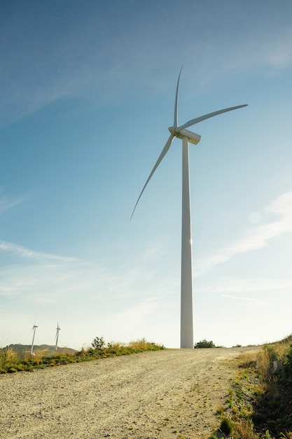 푸른 하늘 위에 전기를 생성하는 언덕에 풍력 터빈. 깨끗하고 생태학적인 에너지 생산 개념입니다.