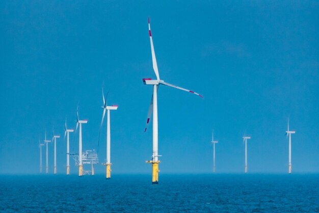 Wind turbines in sea against clear blue sky