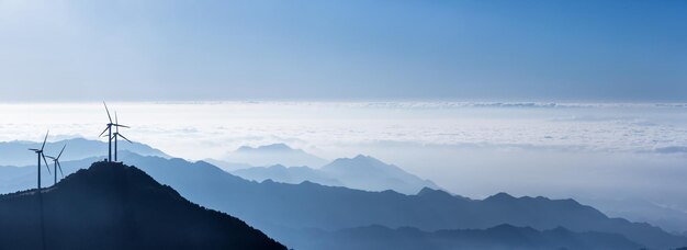 Ветряные турбины и море облаков на участках голубых гор backgrounda панорамный вид на красивые природные пейзажи