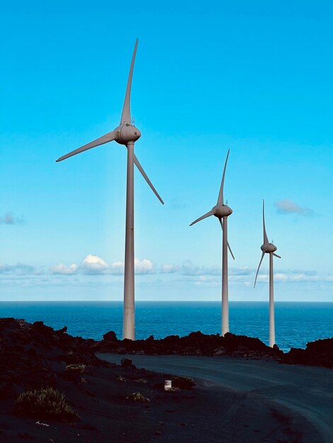 Wind turbines on sea shore against sky