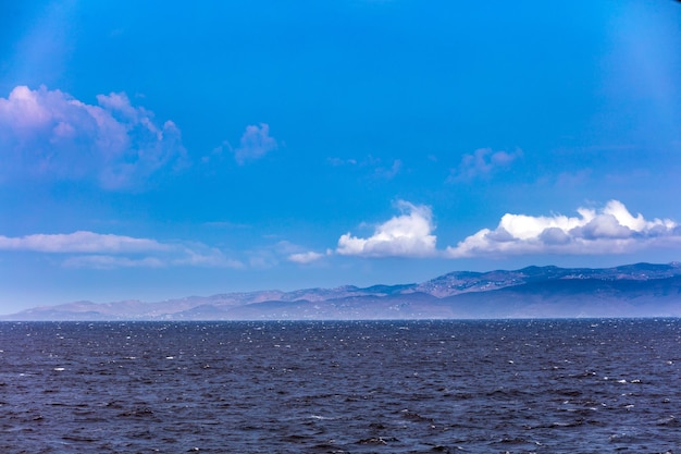 Winderige daggolven op zee en blauwe lucht met witte wolken Griekse eilandachtergrond