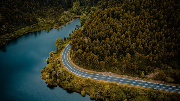 WINDING MOUNTAIN ROAD WITH LAKE FROM AERIAL VIEW WITH DRONE