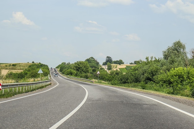 美しい風景を背景に曲がりくねった 2 車線の道路 道路脇の緑 夏の旅行車 写真の田舎の風景 ウクライナ