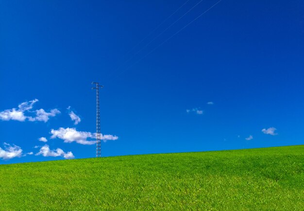 Windmill on field against blue sky