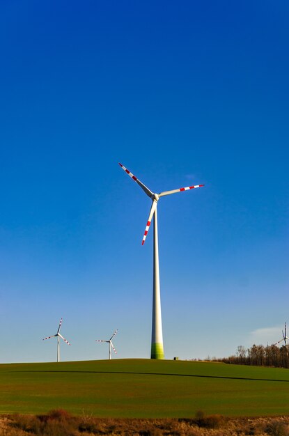 Windmill in a green field against a blue sky. Naturally friendly resource extraction systems.