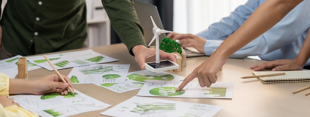 풍차 모델은 재생 가능한 에너지를 나타내고 나무 블록은 생태 도시를 나타내며 환경 문서가 어져있는 녹색 비즈니스 회의 테이블에 배치되었습니다.