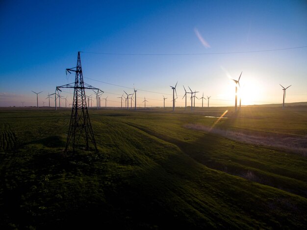 Photo windmills on field against sky during sunset