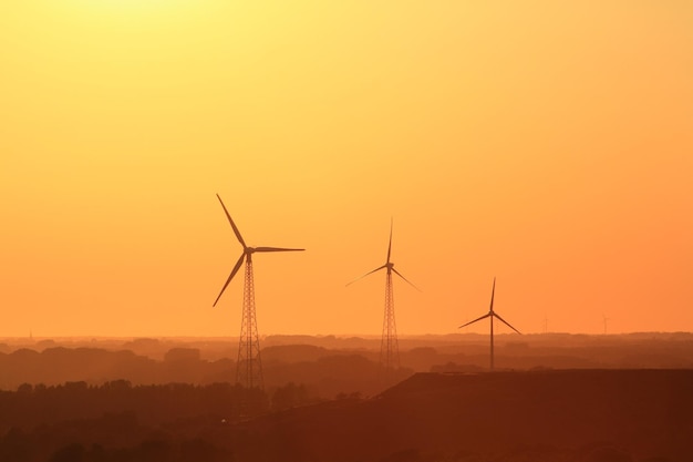Windmills on landscape against sky during sunset