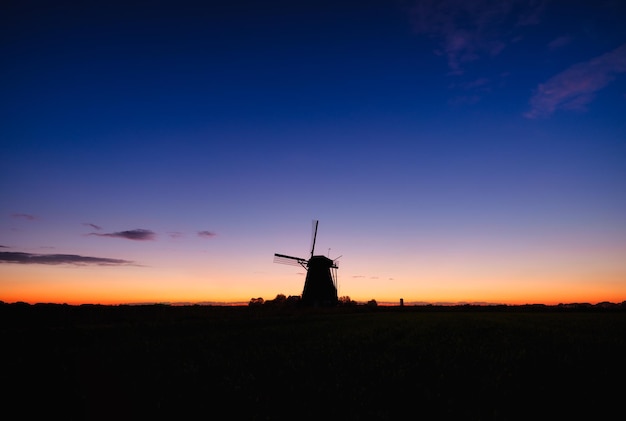 Windmills in the netherlands historic buildings agriculture\
summer landscape during sunset bright sky and the silhouette of a\
windmill photography for design