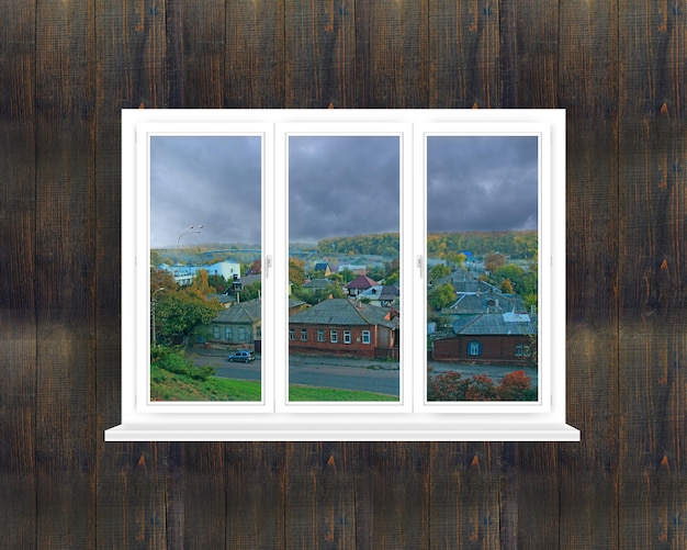 Window on black wall overlooking cloudy landscape in village