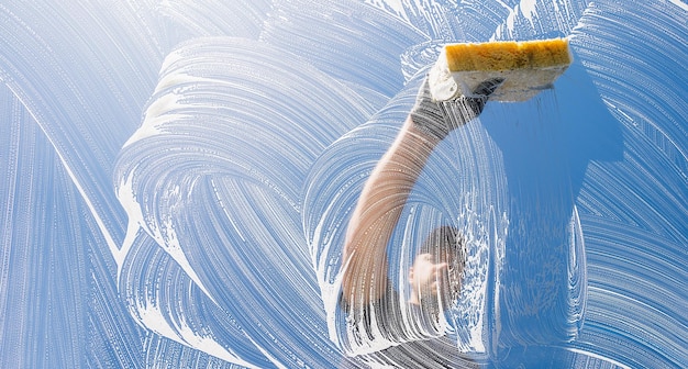 window cleaner cleaning window with sponge on a sunny day