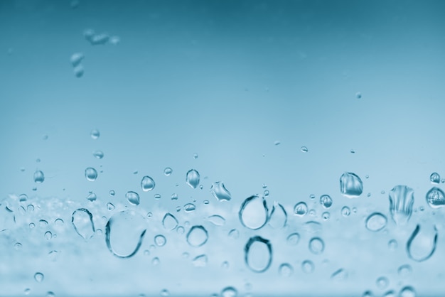 Window glass with frozen drops of rain. Atmospheric mint blue light  with raindrops. Frosty droplets close up. Detailed transparent aquamarine texture in macro with copyspace. Rainy weather