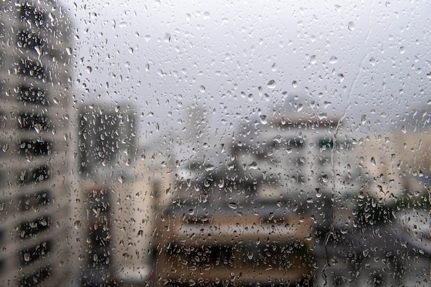 window glass with raindrops showing blurred city in the background