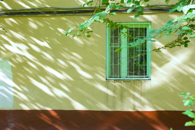 Window in a green colourful frame on a yellow wall. Free space for a text.