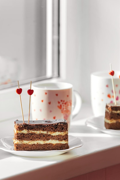 On the window is a festive dessert with tea, two plates with a cake and hearts