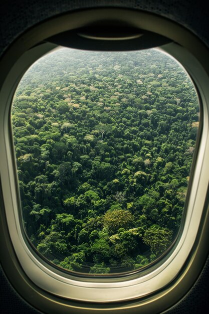 Photo a window of a plane with a view of trees and a plane