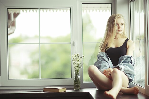 Window sitting young adult girl at home